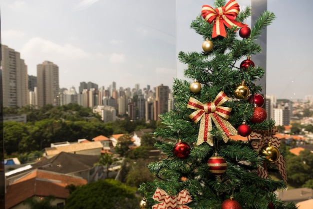 Árbol de Navidad a la luz del día, con un paisaje urbano.