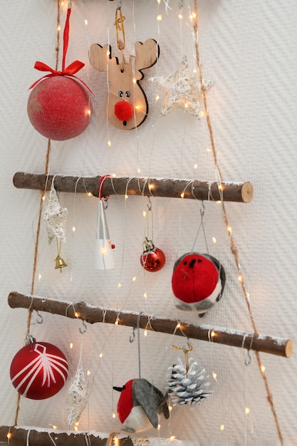 Árbol de Navidad de madera artesanal con juguetes colgados en la pared