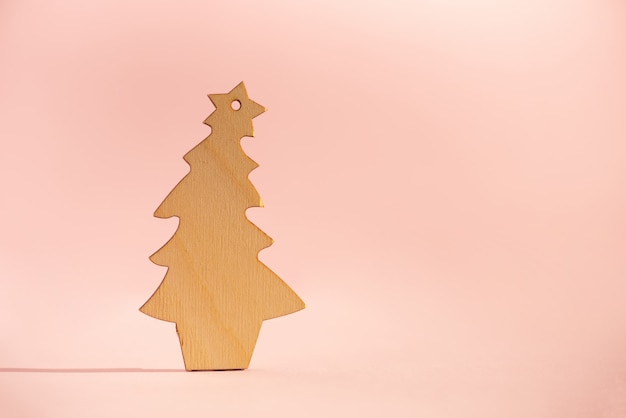 Árbol de navidad de madera en fondo rosado con el espacio de la copia. Fiesta de Año Nuevo.