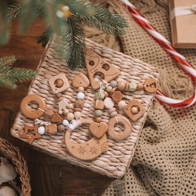 Árbol de Navidad de madera y mordedores para niños en forma de bola de Navidad con cuentas de silicona se encuentran entre los regalos en una canasta de mimbre debajo del árbol de Navidad. Uso de instagram de marco cuadrado