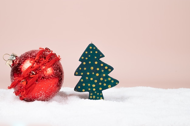 Árbol de Navidad de madera verde con puntos dorados y bola roja sobre superficie pastel. Tarjeta de Navidad. Foto de alta calidad