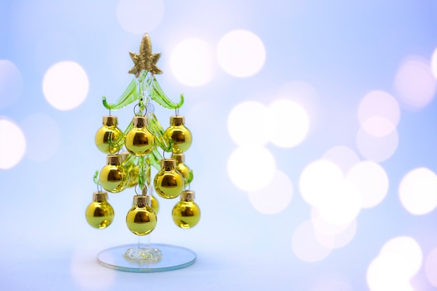 Árbol de Navidad en miniatura hecho de vidrio con bolas de oro aislado sobre un fondo de focos