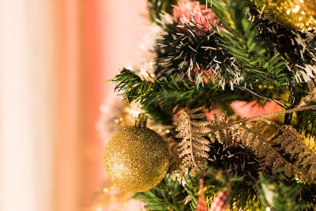 Árbol de Navidad montado con adornos. Bolas rojas, plateadas y doradas, cajas regalo, luces, Papá Noel y otros. Enfoque selectivo.