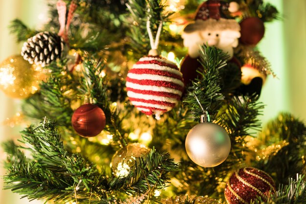 Árbol de Navidad montado con adornos. Bolas rojas, plateadas y doradas, cajas regalo, luces, Papá Noel y otros. Enfoque selectivo.