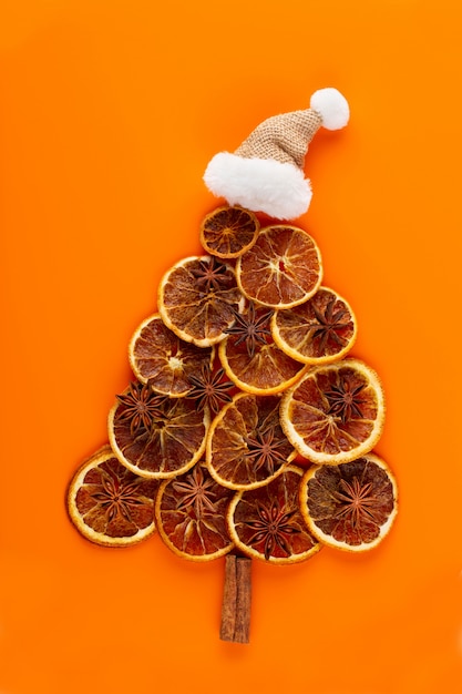 Árbol de Navidad de naranjas secas sobre fondo naranja.