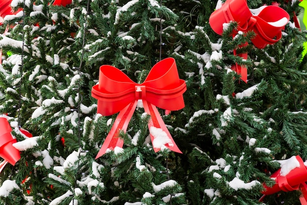 Árbol de Navidad en la nieve con un gran lazo rojo y un fondo borroso Decoraciones de la calle Concept de la ciudad para Navidad