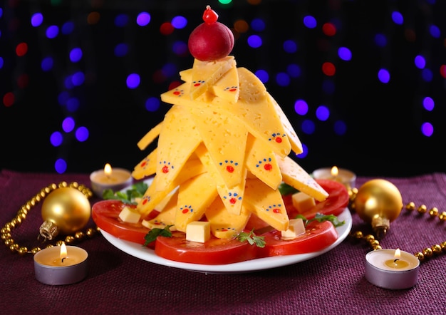 Árbol de Navidad de queso en la mesa sobre fondo oscuro