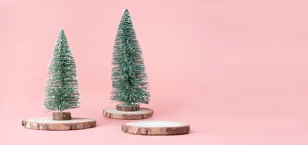 Árbol de navidad en la rebanada de madera del registro con la actual caja en fondo rosado en colores pastel del estudio