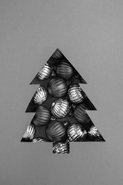 Árbol de Navidad recortado sobre el fondo gris y relleno de bolas negras. De cerca.