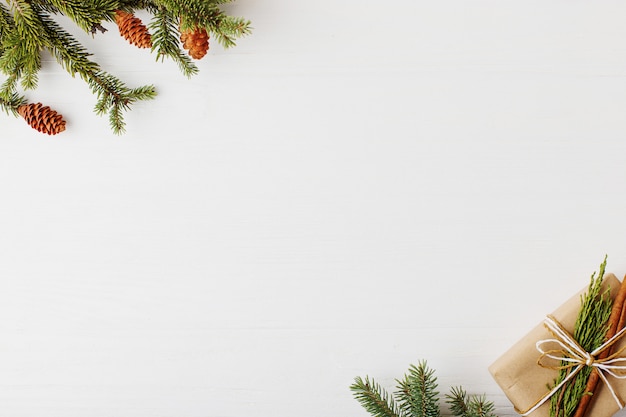 Árbol de Navidad, regalo y conos en una mesa de madera blanca Preparación para escribir el texto,.