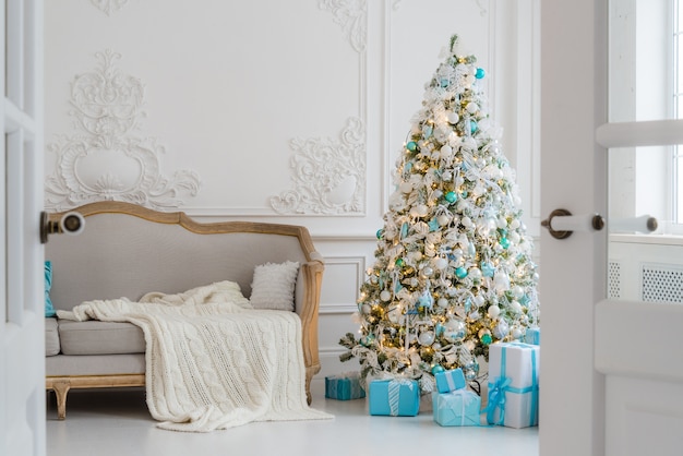 Árbol de Navidad con regalos regalos debajo en la sala de estar