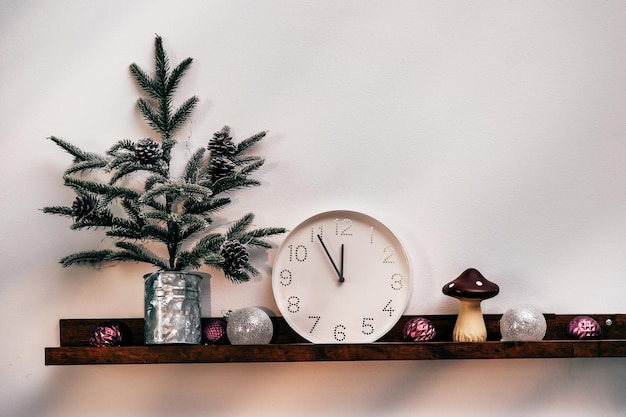 Árbol de Navidad reloj blanco y decoraciones frente a la pared de madera