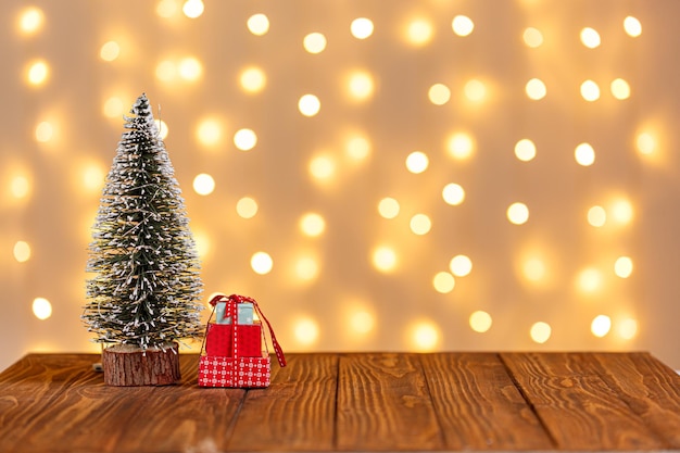 Árbol de Navidad reloj trineo muñeco de nieve velas regalos sobre un fondo de madera y luces de fondo