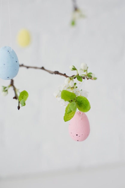 Árbol de Pascua en jarrón azul con huevos de colores sobre un fondo blanco.