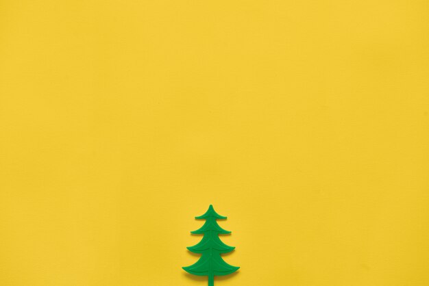 Árbol plástico de madera de pino del juguete en amarillo. Temporada mínima de Navidad plana. copyspace