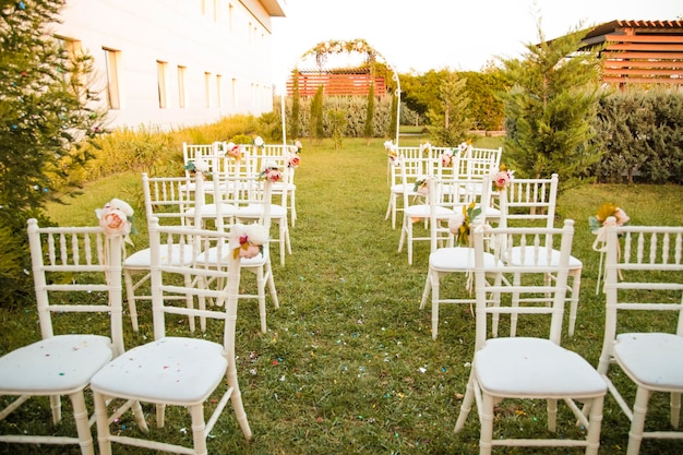 Área de ceremonia vacía Paisaje de flores y un camino de vegetación Sillas blancas Hermosa decoración floral del lugar de la boda y detalles de la ceremonia