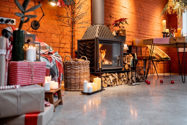 Área da lareira de um belo interior em estilo loft com tijolos reais e pisos de concreto decorados para o feriado de ano novo. O conceito de conforto doméstico