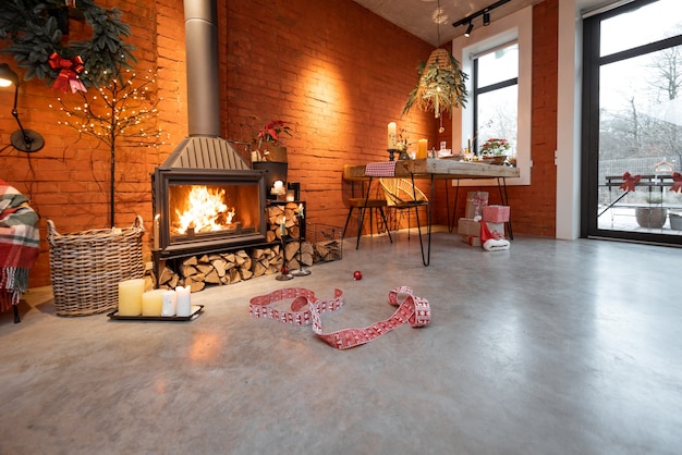 Área da lareira de um belo interior em estilo loft com tijolos reais e pisos de concreto decorados para o feriado de ano novo. O conceito de conforto doméstico