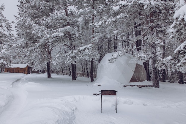 Área de glamping com tenda de cúpula de churrasco e despensa no inverno nevado ao ar livre