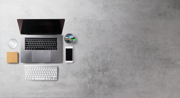 Área de trabalho da mesa de escritório de vista superior plana leiga com laptop e smartphone em fundo cinza. Copie o espaço.