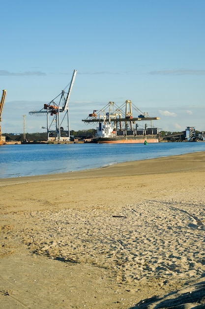 Área industrial nos guindastes grandes da costa no porto de fundo