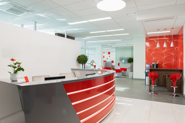 Área de recepción para visitantes de oficina moderna con interior rojo y blanco.