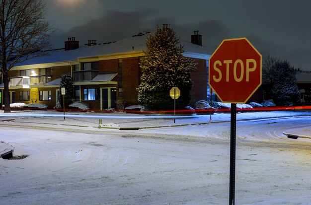 Área residencial de inverno na rua à noite com carros estacionados e cobertos pela neve