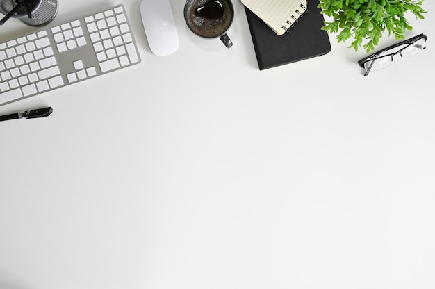 Área de trabajo de escritorio de mesa de oficina de vista superior con teclado de computadora en blanco y suministros de oficina