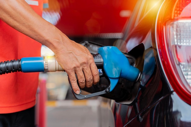 Foto reabastecendo o carro em uma bomba de combustível de posto de gasolina man motorista de homem reabastecendo e bombeando óleo de gasolina o carro com combustível no posto de reabastecimento