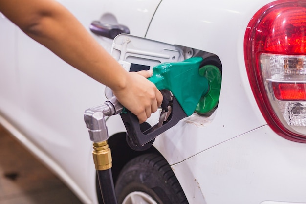 Foto reabastecimiento de combustible llene el coche con gasolina en la gasolinera y la bomba de gasolina llene la boquilla de combustible en el depósito de combustible del coche