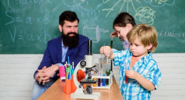 Foto reacción química fascinante profesora y alumnos con tubos de ensayo en el aula clases escolares interesantes educación escolar experimento de química club escolar explicando química a los niños