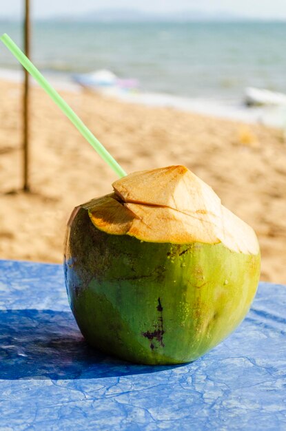 Readytodrink coco coco verde fresco contra el telón de fondo de la orilla de arena del mar