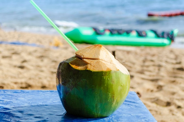 Readytodrink coco coco verde fresco contra el telón de fondo de la orilla de arena del mar