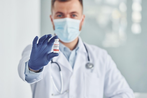 Reagenzglas mit COVID19-Impfstoff halten Professioneller Sanitäter im weißen Kittel ist in der Klinik