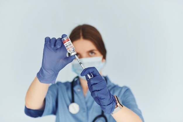 Reagenzglas mit Impfstoff Junge Ärztin in Uniform ist drinnen