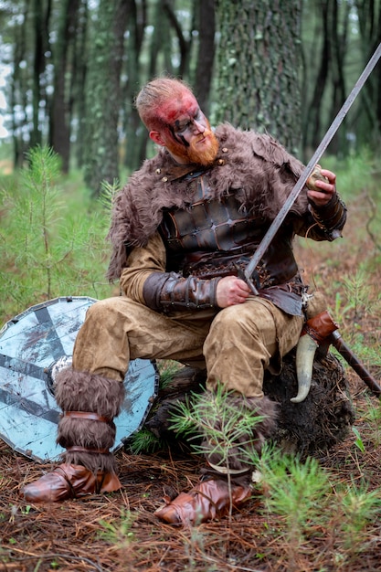 Real viking afiar sua espada com uma pedra