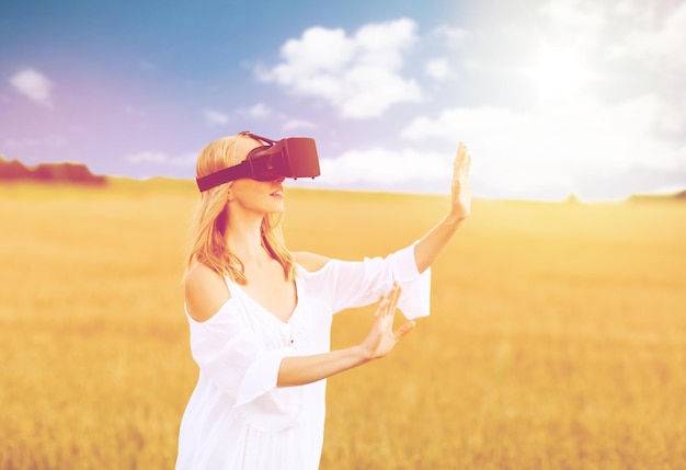 realidade aumentada, jogos, férias de verão, tecnologia e conceito de pessoas - jovem feliz com fone de ouvido de realidade virtual ou óculos 3d no campo de cereais tocando algo