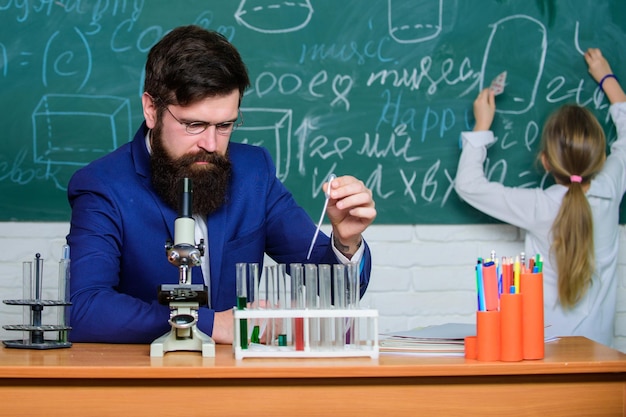 Realizando un experimento Profesor y alumno Profesor masculino dando una lección en el aula de ciencias Profesor de escuela pública o privada Profesor de química con microscopio y tubos de ensayo en la lección