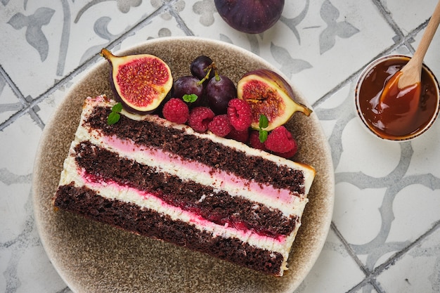 Rebanada de bizcocho de chocolate relleno de frambuesa y crema de chocolate blanco y frutos del bosque