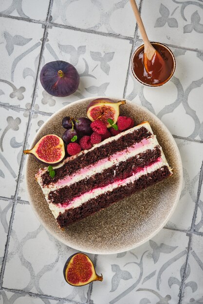 Rebanada de bizcocho de chocolate relleno de frambuesa y crema de chocolate blanco y frutos del bosque