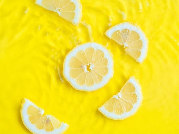 Rebanada de cítricos de limón amarillo intenso en agua con fondo de verano de textura ondulada
