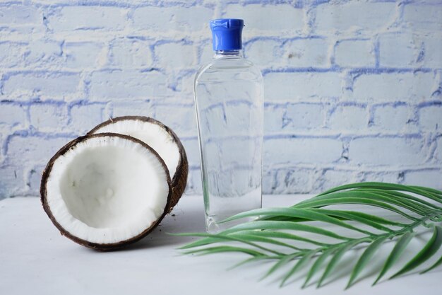 Rebanada de coco fresco y botella de aceite para el cabello en una mesa