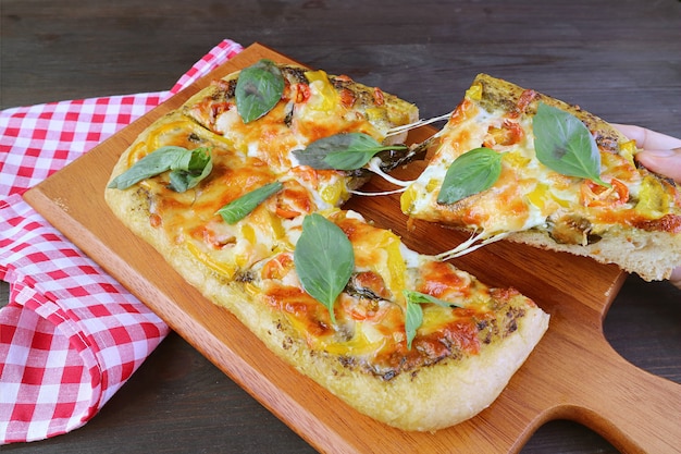 Rebanada de deliciosa pizza vegetariana al pesto con queso de estiramiento extraído de la placa de pruebas