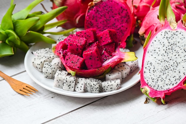 Foto rebanada de fruta de dragón y cortada a la mitad en un plato blanco con fondo de pitahaya fruta de dragón púrpura blanca y roja fresca tropical en el concepto de fruta saludable de tailandia asiática