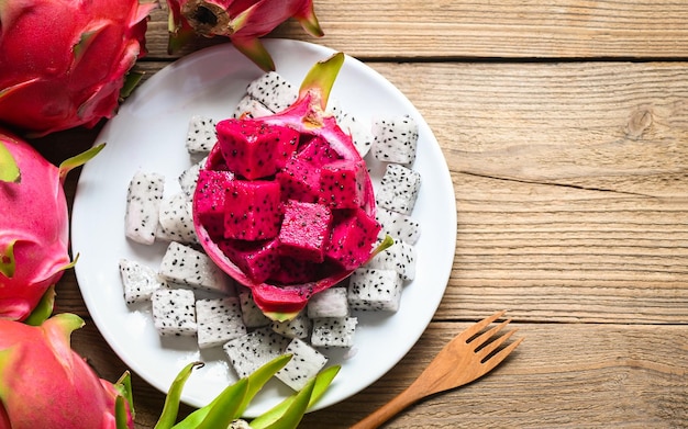 Rebanada de fruta del dragón en un plato blanco con fondo de pitahaya fruta de dragón púrpura blanca y roja fresca tropical en la vista superior del concepto de fruta saludable de tailandia asiática