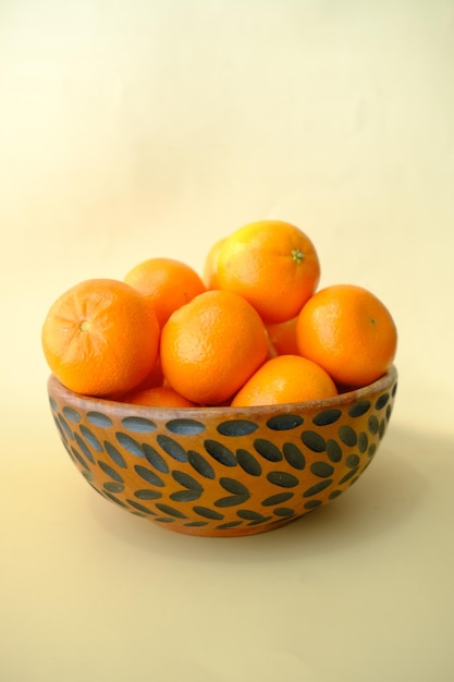 Rebanada de frutas naranjas en un tazón sobre fondo amarillo claro