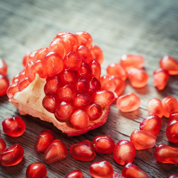 Rebanada de granada madura y semillas de fruta de granate rojo en la mesa