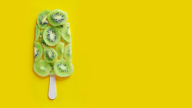 Rebanada de kiwi Helado en una pancarta de palo con fondo amarillo Trozos de kiwi Pancarta de verano con kiwi