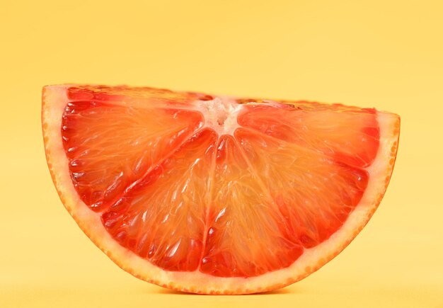 Rebanada madura de cítricos de naranja roja sangre sobre fondo amarillo Primera foto en el conjunto