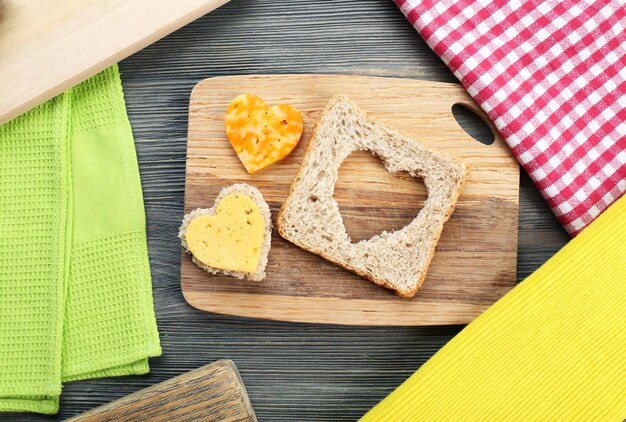 Rebanada de pan con corte en forma de corazón y queso en la mesa de cerca